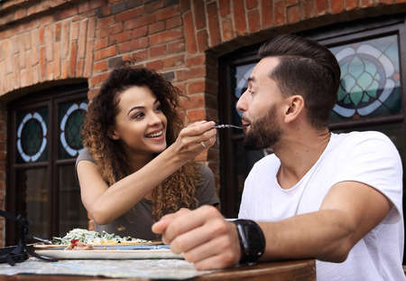 Young couple enjoying coffee at a street cafe and  laughingの写真素材