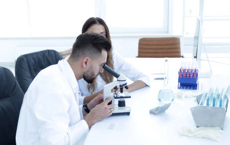 scientist looking in a microscope sitting in the lab.の写真素材