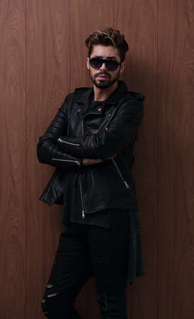 Portrait of young handsome fashionable man against wooden wall.