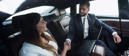 man and woman shaking hands in carの写真素材