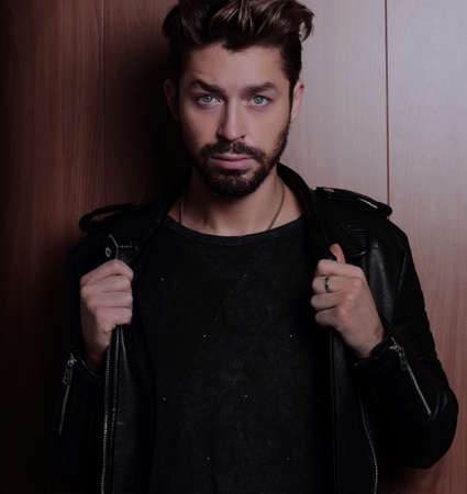 Portrait of young handsome fashionable man against wooden wall.