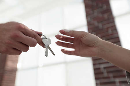 Cropped image of estate agent giving house keys to man in office