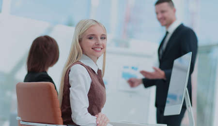Portrait of a smiling businesswoman sitting at a table with coll