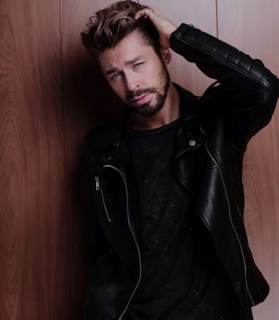 Portrait of young handsome fashionable man against wooden wall.の写真素材