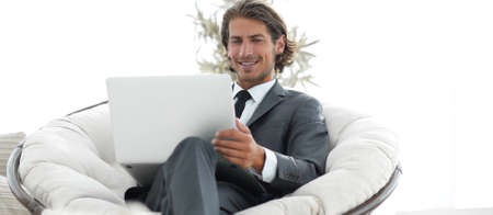 successful businessman with laptop sitting in a large comfortable armchaiの写真素材