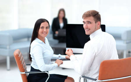 members of the business team sitting at Desk and looking at camera .