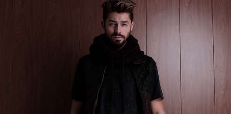 Portrait of young handsome fashionable man against wooden wall.