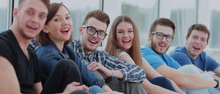 A group of happy students sitting on a window sill and smiling