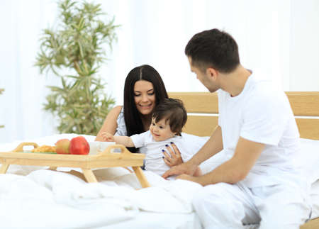 Family taking the breakfast on the bed in the bedroomの写真素材