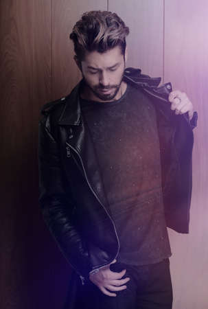 Portrait of young handsome fashionable man against wooden wall.