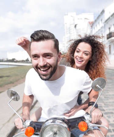 Happy cheerful couple riding vintage scooter outdoors.の写真素材