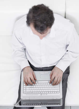 view from the top.man working on laptop lying on a sofa.の写真素材
