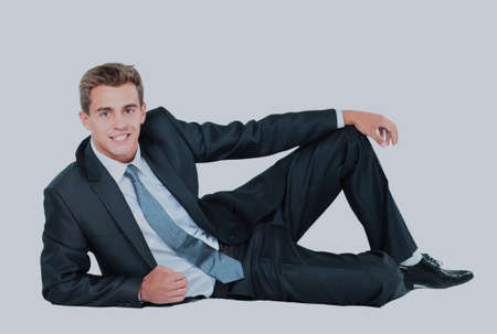 Portrait of business man sitting on the floor isolated over white background.の写真素材