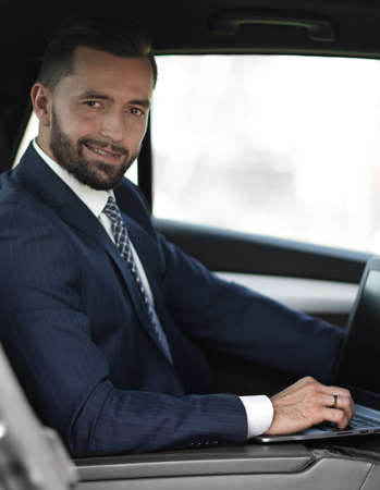 Close-up of a businessman with a laptop sitting in the carの写真素材