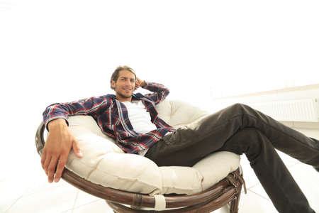 Serious guy rests sitting in a large comfortable chair. side view.の写真素材