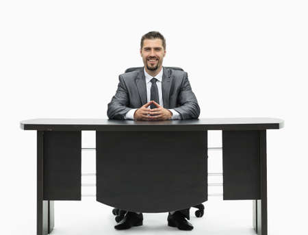 confident businessman sitting behind a Desk. isolated on white.の写真素材