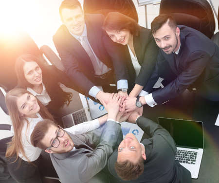 business team with hands clasped together on Desk