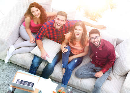 view from the top.a group of laughing friends sitting on the sofaの写真素材