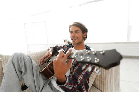 guy with guitar sitting on sofa in living room. concept of a lifestyle