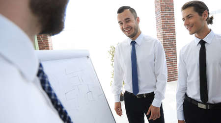 businessman pointing business team on a blank flipchart.