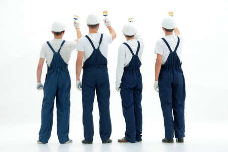 rear view.team of construction workers paint a wall.