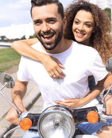 Happy cheerful couple riding vintage scooter outdoors.の写真素材