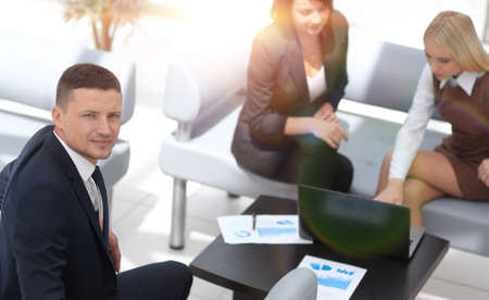 money Manager sitting next to colleagues and looking at the camera.の写真素材