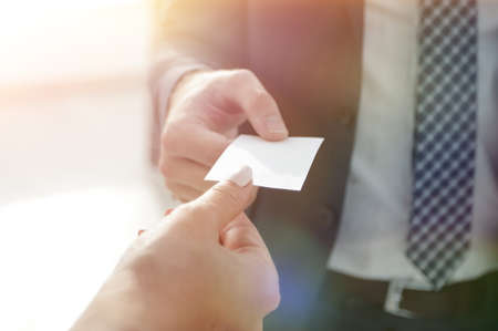 Close-up of two businesspeople exchanging visiting cardの写真素材