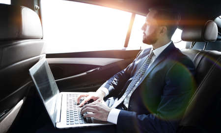 Businessman working with laptop sitting in car
