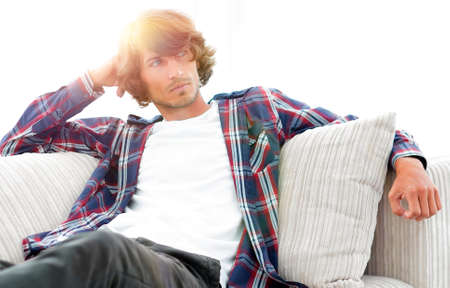 serious modern guy sitting on the couchの写真素材