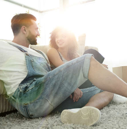 Happy married couple sitting on the carpet in a new apartment.の写真素材