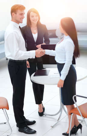 business partners shaking hands while standing in the lobby of the office.の写真素材