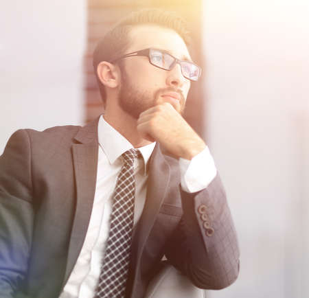 handsome businessman thinks, sitting on couch in his office