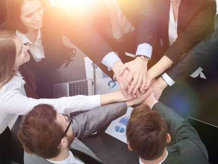 business team with hands clasped together on Desk