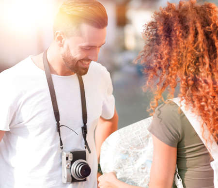 Young couple walking and looking at a guide while looking happy