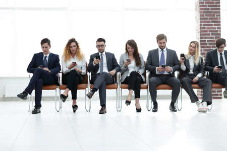 employees with smartphones sitting in the lobbyの写真素材