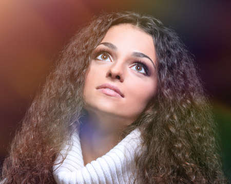 beautiful women with long hair in a sweater looking up.の写真素材