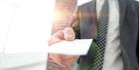 Businessman giving a card. Close-up photo in loft officeの写真素材