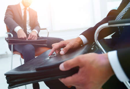 Man in a classic suit holds a brown briefcase close-upの写真素材