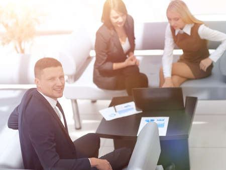 money Manager sitting next to colleagues and looking at the came