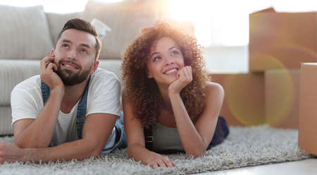 Young couple lying on the rug on the background of a new apartme