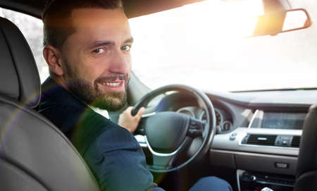 businessman sitting at the wheel of a prestigious carの写真素材