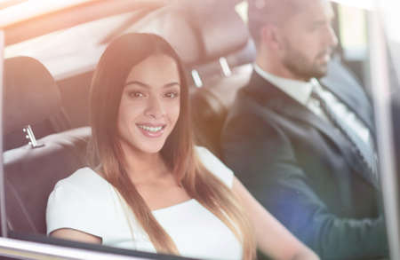 Portrait of a woman in a white dress in her car in the back seatの写真素材