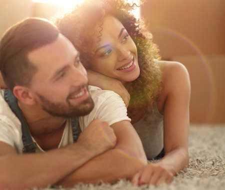 Happy couple lying on the carpet on the blurred backgroundの写真素材