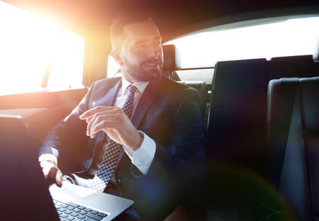 businessman sitting in the back seat in the car and pointing hisの写真素材
