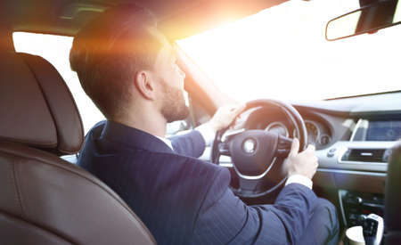 businessman sits at the wheel in his car and looks at the road