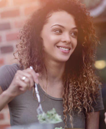 Young woman enjoying food at a street cafe in the hot summer sunの写真素材