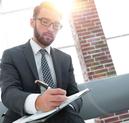 Businessman writing in a notebook in an office