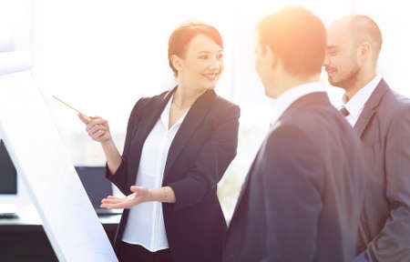 business woman showing a business team information on the flipch