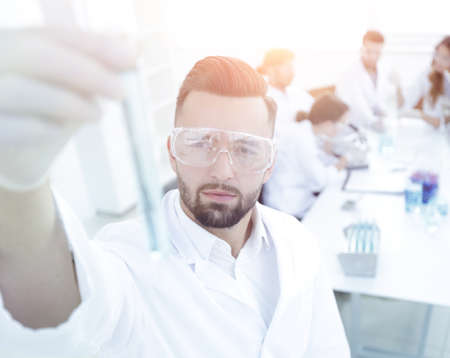image is blurred. young scientist holding tube with the reagents